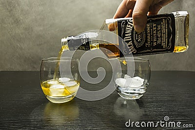 Whiskey pouring from a bottle into a glass of ice. Editorial Stock Photo